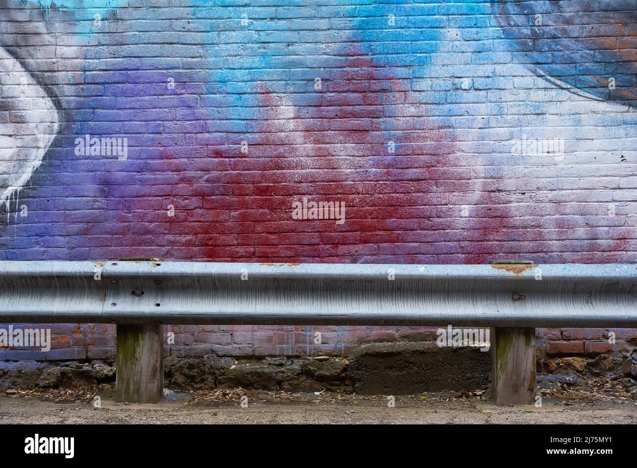 Mur de briques peint et rail de garde en métal dans la ruelle arrière de la ville du Midwest. Banque D'Images