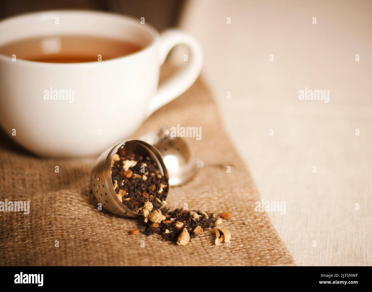 Infuseur de thé qui renverse le thé Chai en vrac; une tasse de thé Chai Banque D'Images