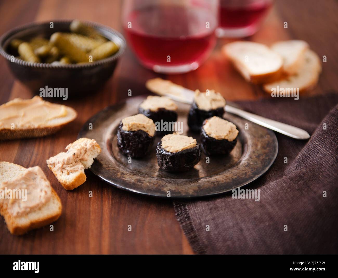 Pruneaux farcis avec foie gras sur un plat métallique; pain et foie gras; cornichons; vin Banque D'Images
