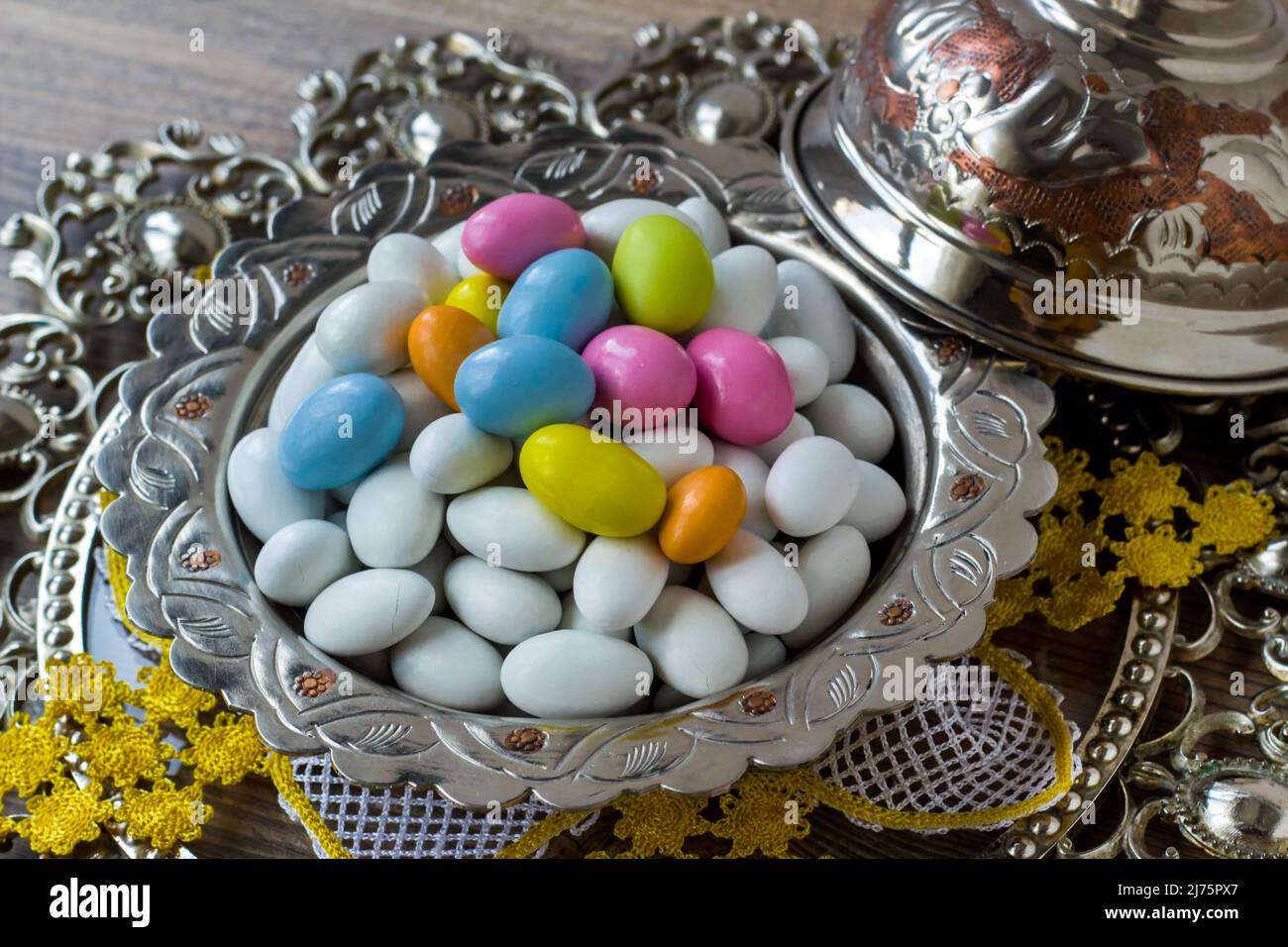 Tons traditionnels, blancs et pastel, bonbons aux amandes enrobés de chocolat dans un bol rétro argenté, sur une surface en bois Banque D'Images