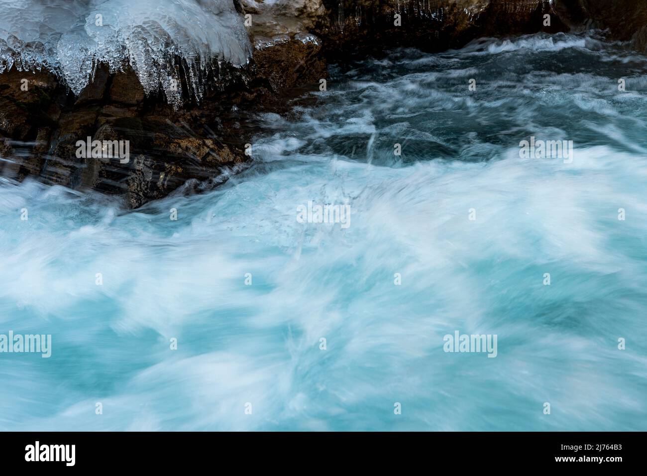 L'eau rapide du Rissbach forme du jet et du courant. Les structures de glace et les rochers formés sur la rive du ruisseau de montagne, bordent l'image. Pris en hiver au Tyrol, en Autriche dans l'Eng, près de l'Ahornboden. Banque D'Images
