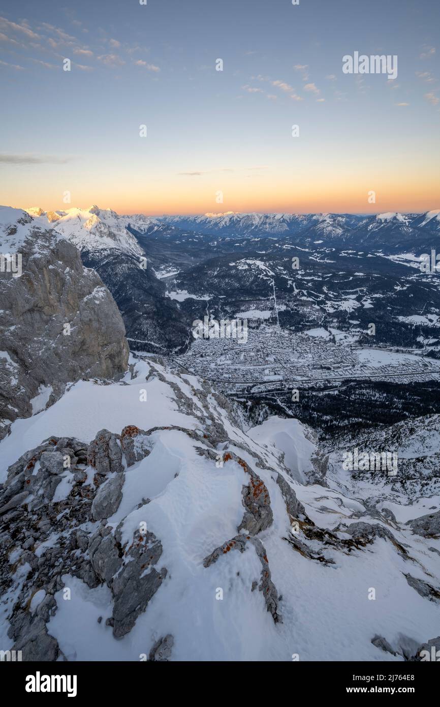 Vue de l'ouest du Karwendel, sur les rochers et la neige ind e Werdenfelser Land en hiver, avec la ville de marché Mittenwald, le Kranzberg, les Prealps bavarois et vers Garmisch-Partenkirchen, avec le Zugspitze en arrière-plan, tandis que les couleurs douces de l'aube sont dans le ciel. Banque D'Images