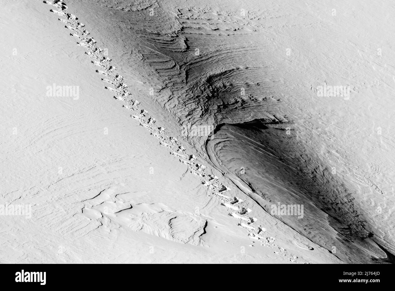 Une seule piste de raquettes dans le Karwendel sur une pente de montagne dans la neige. Le terrain escarpé montre des structures dans la neige. Banque D'Images Une seule piste de raquettes dans le Karwendel sur une pente de montagne dans la neige. Le terrain escarpé montre des structures dans la neige. Banque D'Images