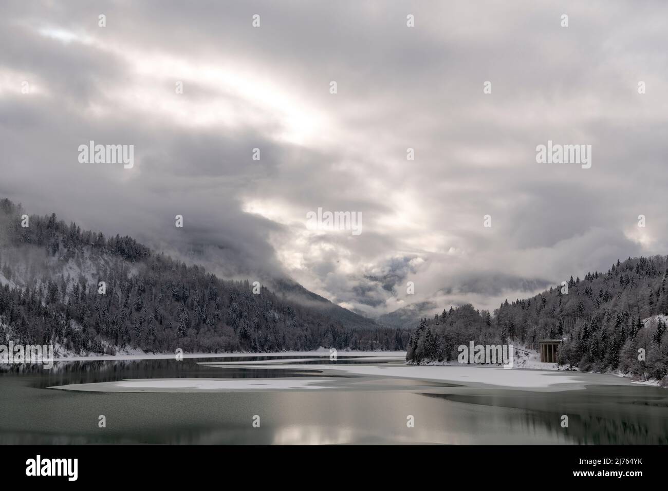 La Sylvensteinspeichersee, au bord des montagnes Karwendel dans les Alpes bavaroises, en hiver avec de la neige et en partie avec de la glace, ainsi que l'atmosphère de nuages. Banque D'Images La Sylvensteinspeichersee, au bord des montagnes Karwendel dans les Alpes bavaroises, en hiver avec de la neige et en partie avec de la glace, ainsi que l'atmosphère de nuages. Banque D'Images
