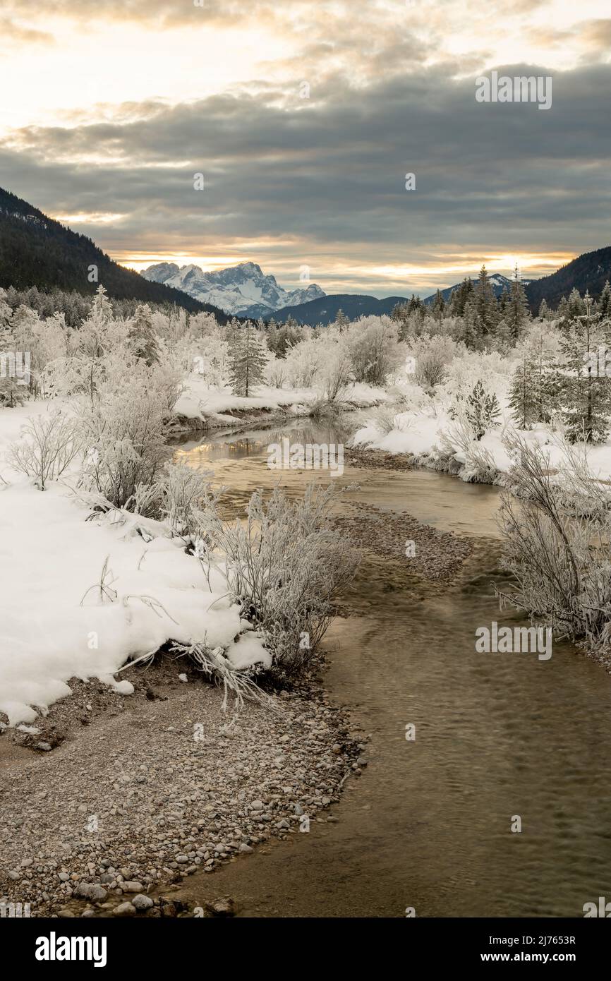 Un petit ruisseau latéral de l'Isar, vents à travers le paysage enneigé couvert de givre en hiver. En arrière-plan, la Zugspitze et la douce lumière du soir. Banque D'Images Un petit ruisseau latéral de l'Isar, vents à travers le paysage enneigé couvert de givre en hiver. En arrière-plan, la Zugspitze et la douce lumière du soir. Banque D'Images
