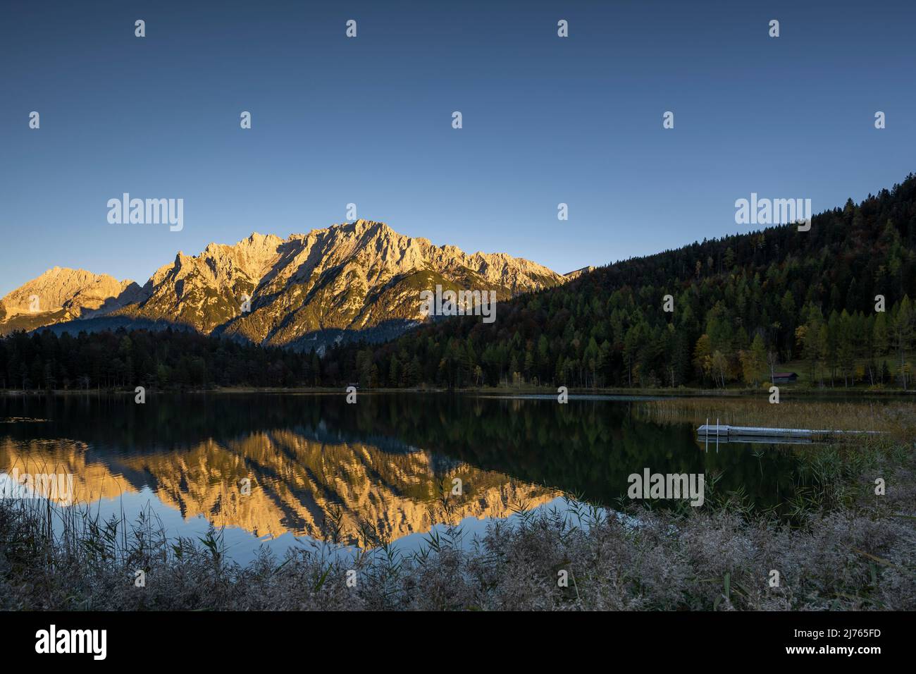 Le Lautersee au-dessus de Mittenwald reflète l'alpenglow doré du soleil du soir comme un sceau parfait. Banque D'Images Le Lautersee au-dessus de Mittenwald reflète l'alpenglow doré du soleil du soir comme un sceau parfait. Banque D'Images