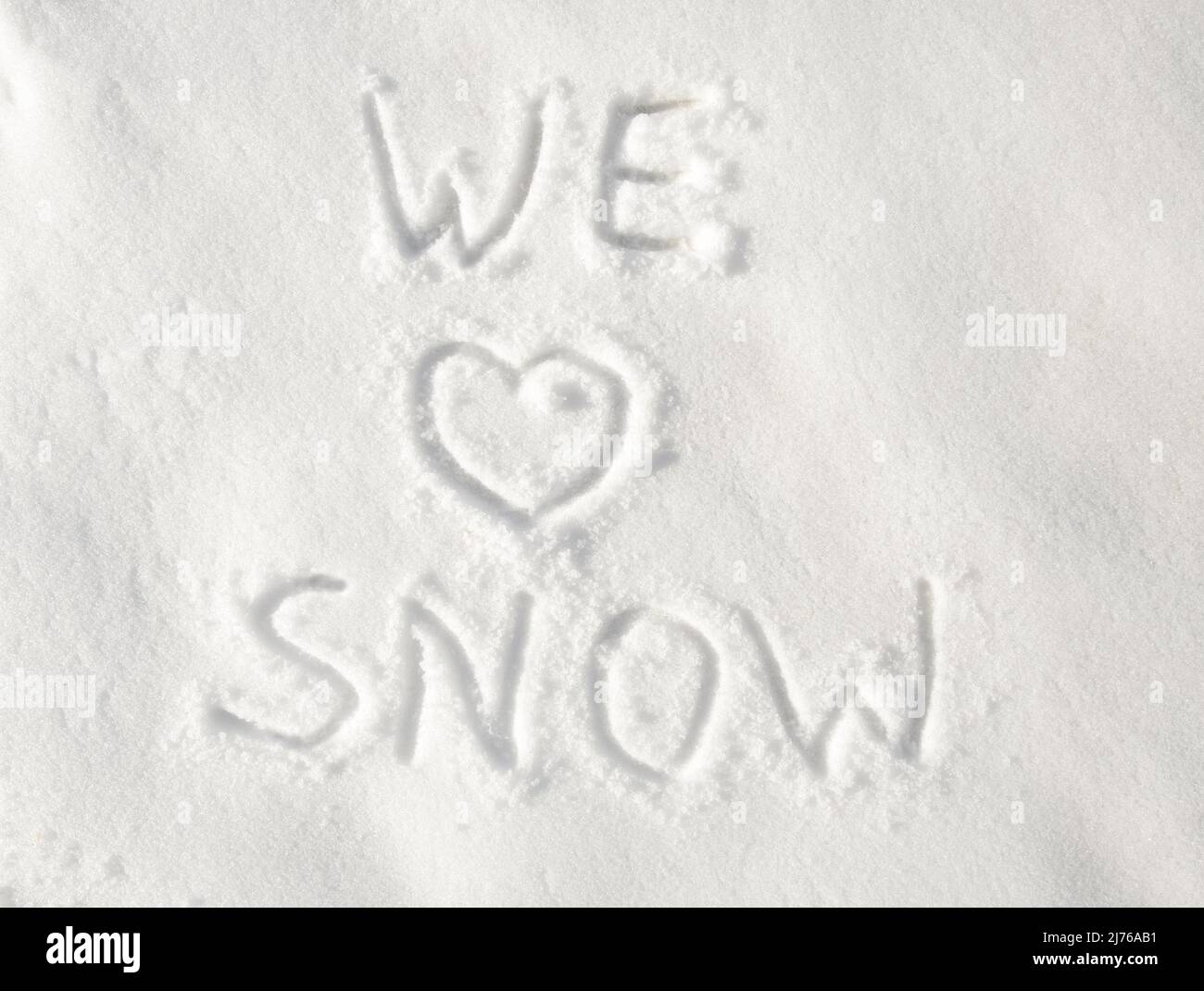 Texte « nous aimons la neige » écrit dans la neige; avec un coeur pour l'amour Banque D'Images