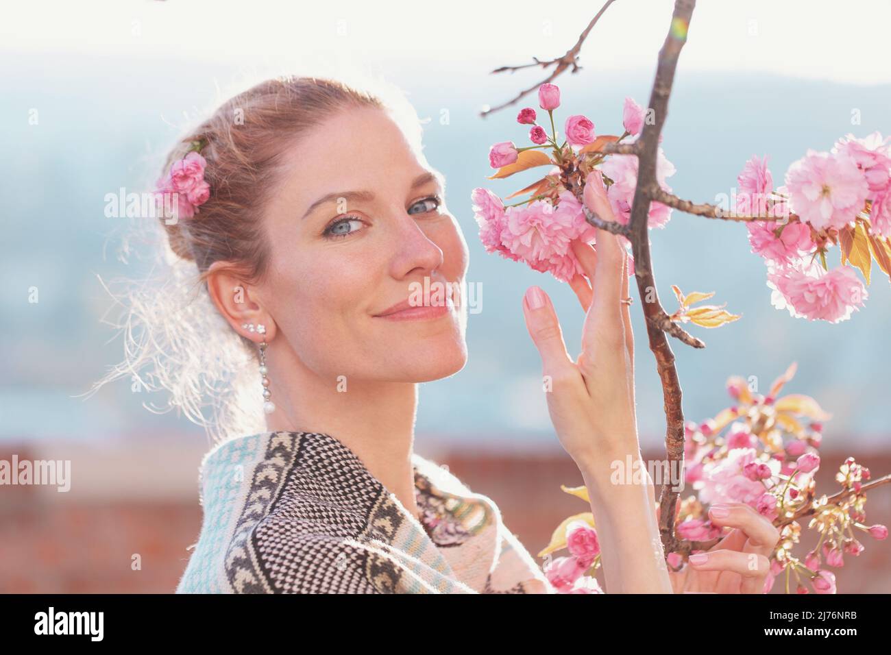 Jeune femme blanche douce tenant une fleur de cerisier au printemps Banque D'Images