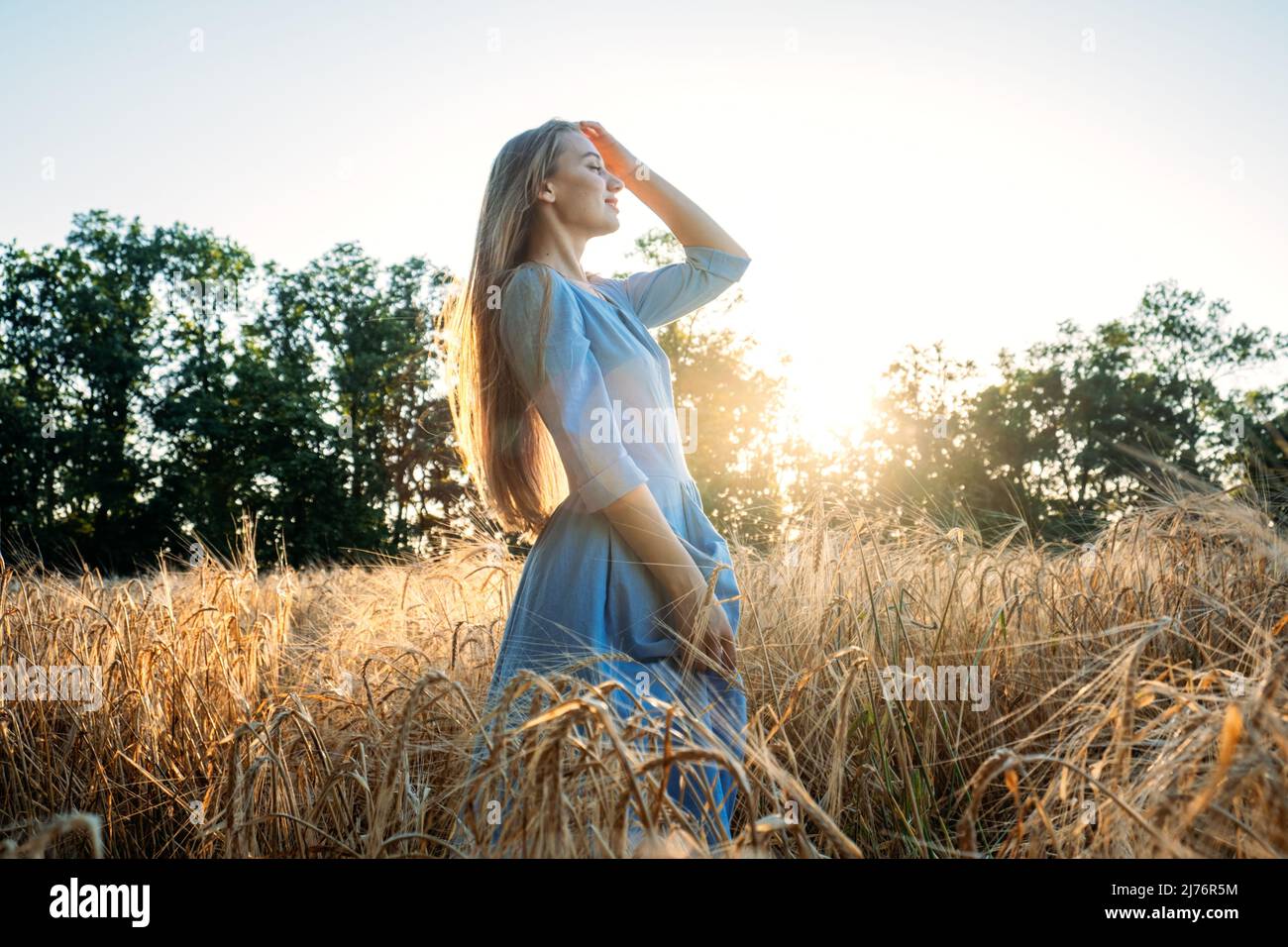 Connectez-vous à la nature, ralentissez, soyez présent, entrez dans vos sens. Paisible seule jeune femme en robe marchant sur le champ de blé au coucher du soleil le jour d'été Banque D'Images