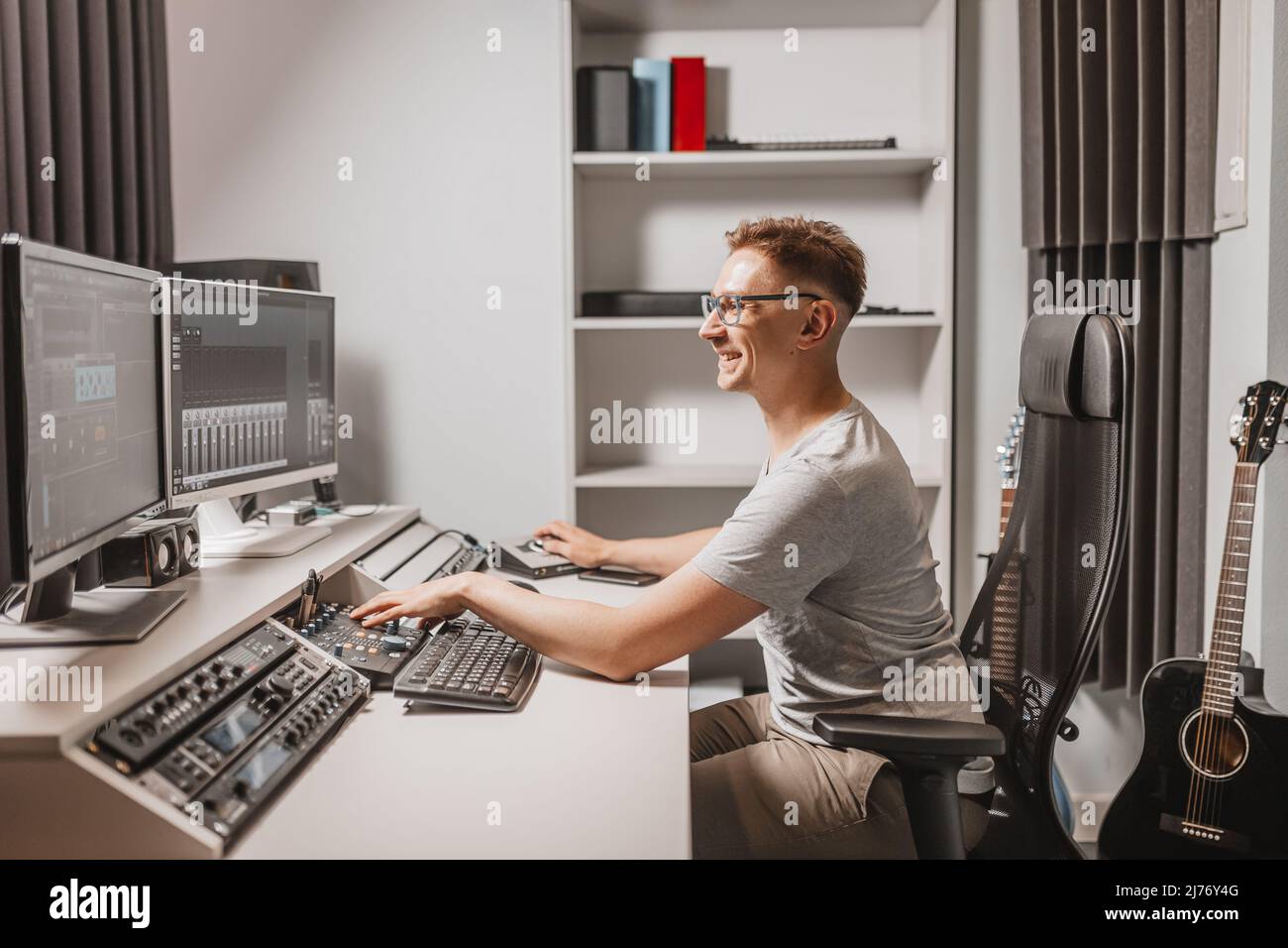 Homme travaillant dans un studio de musique utilisant un ordinateur portant des lunettes. Piste de mixage et de travail de l'ingénieur du son. Le programmeur regarde à l'écran pendant l'écoute Banque D'Images