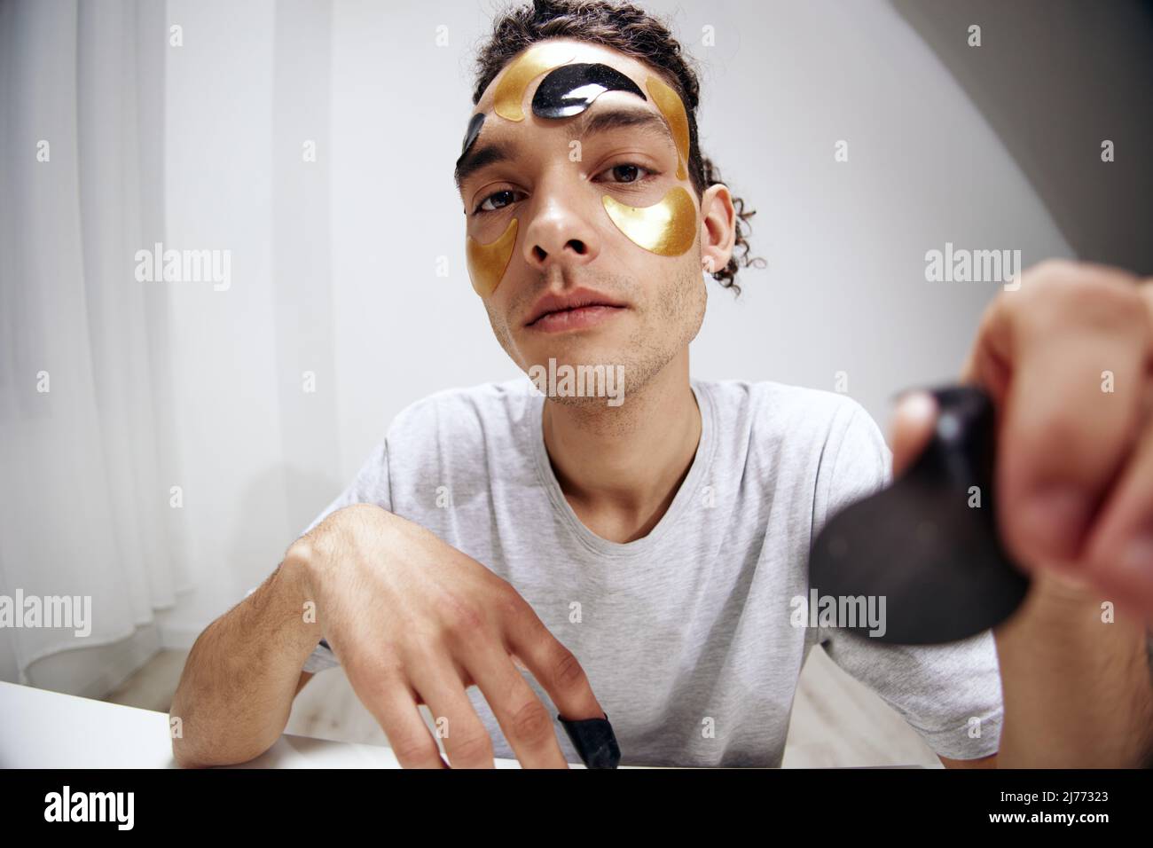 Un jeune homme dans un T-shirt blanc avec des taches sur le soin du visage rajeunissant peau Banque D'Images