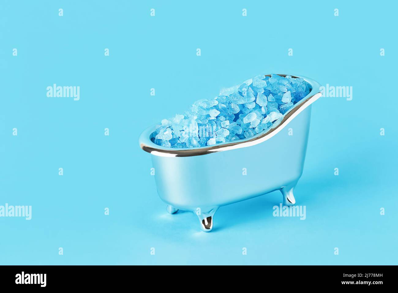 Sel de bain bleu dans une petite baignoire sur fond bleu. SPA, concept de soins du corps. Copier l'espace pour le texte Banque D'Images