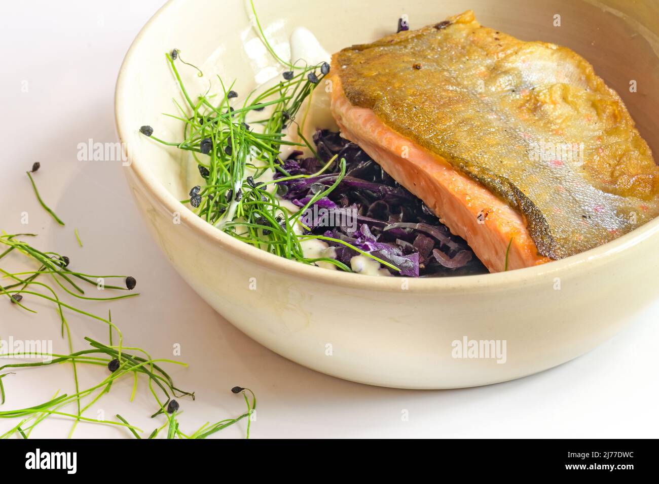 Filet de poisson grillé sur la peau avec des kimchi de chou rouge, sauce crème et pousses servis dans un bol, foyer choisi, champ étroit Banque D'Images