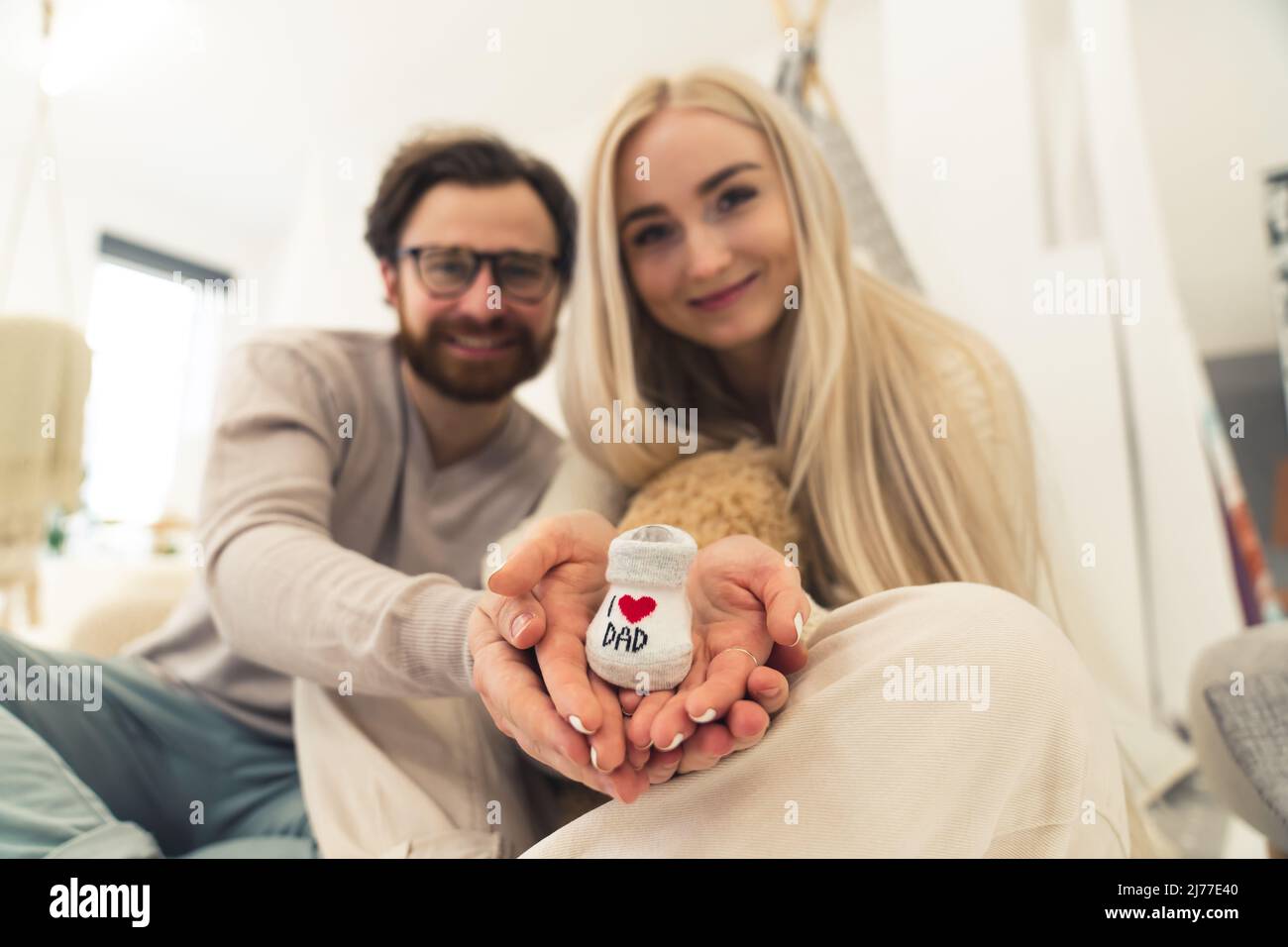 Concept de planification familiale. Jeune couple caucasien excité marié tenant une chaussure blanche pour bébé. Mise au point au premier plan. Photo de haute qualité Banque D'Images