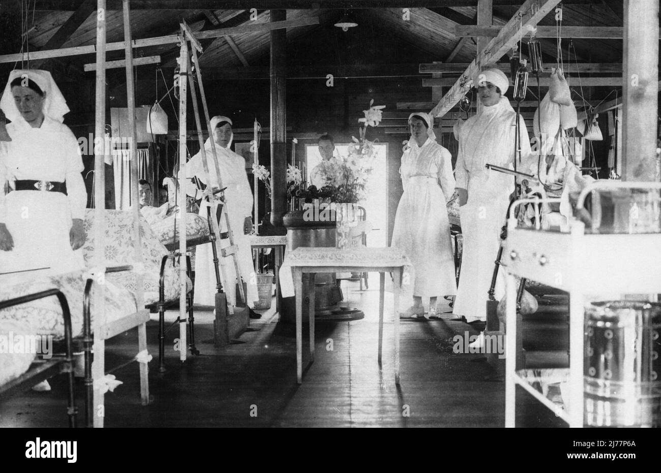 Quatre infirmières se tiennent près de leur lit pendant qu'un homme pousse un chariot dans l'allée jusqu'à la table au milieu. Banque D'Images