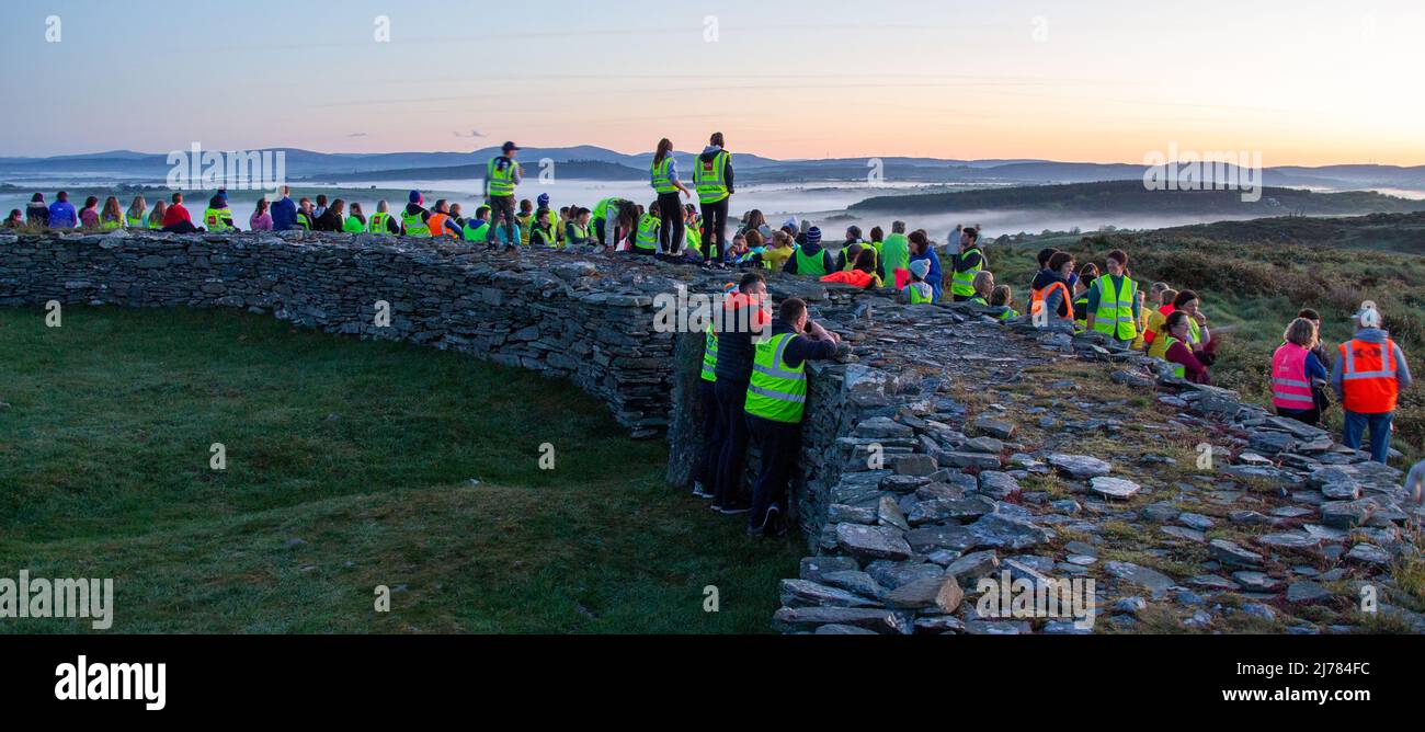 La foule regarde le lever du soleil après la tombée de la nuit dans la marche lumineuse. Knockdrum anneau en pierre fort, West Cork, Irlande Banque D'Images