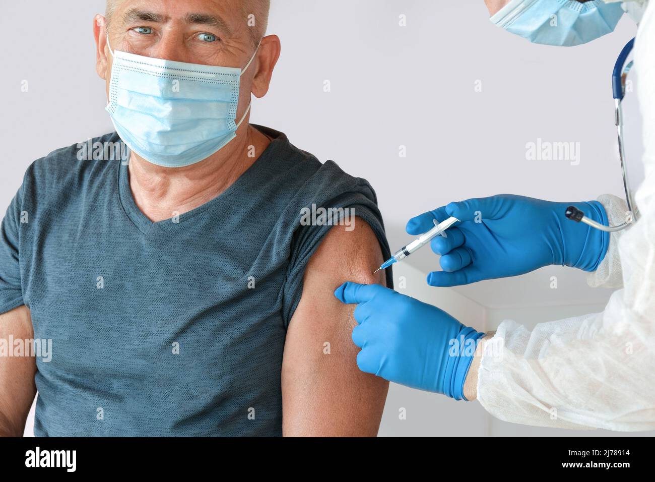 Médecin vaccinant l'homme supérieur en clinique. Vaccination des personnes âgées. Médecin donnant COVID19 injection de vaccin coronavirus à l'homme mature dans le masque facial. Banque D'Images