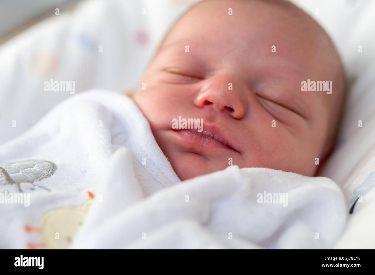 portrait d'une jeune fille en pyjama blanc doux endormie dans son berceau après avoir été nourrie de lait maternel Banque D'Images