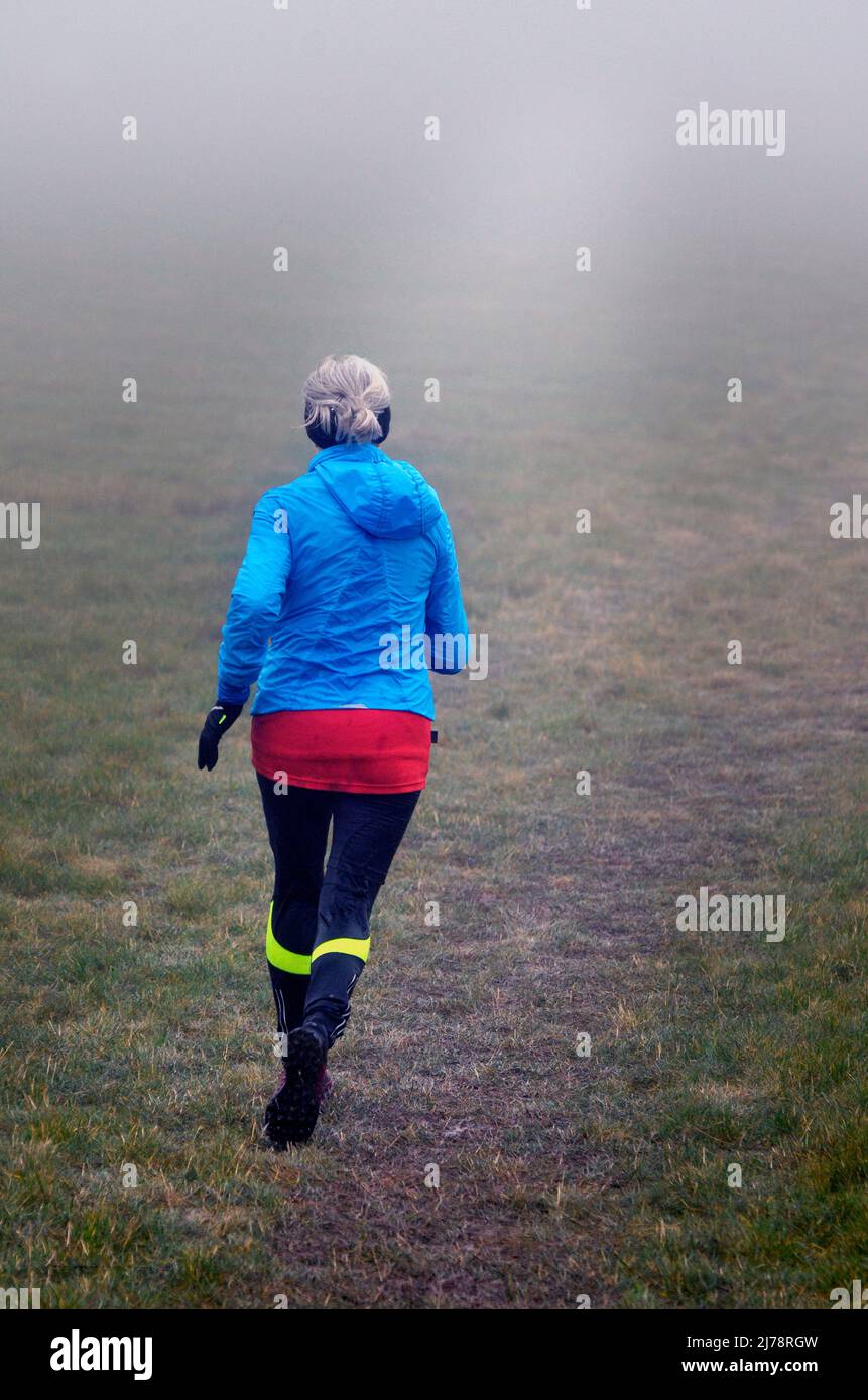 femme âgée solitaire en train de courir sur le champ de la brume Banque D'Images