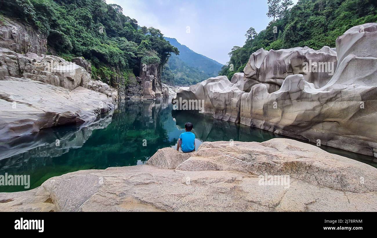 Jeune enfant isolé assis sur une pierre blanche brillante naturellement formée dans une forme unique au lit de rivière sec image est prise à Sliang wah Umngot amkoi jaintia Banque D'Images