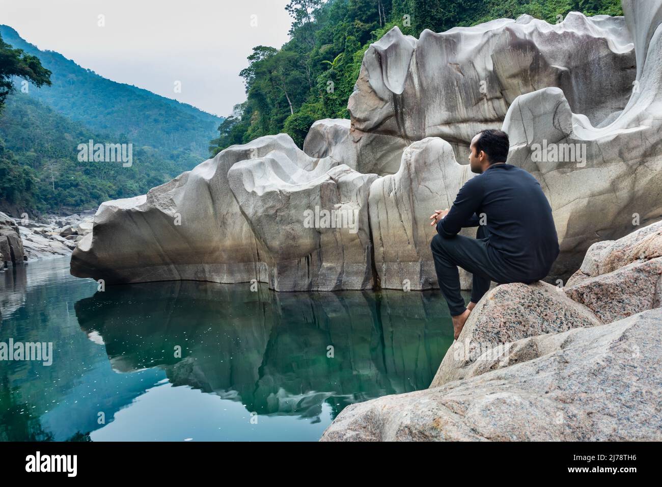 Jeune homme isolé assis sur une pierre blanche brillante naturellement formée dans une forme unique au lit sec de rivière image est prise à Sliang wah Umngot amkoi jaintia hi Banque D'Images