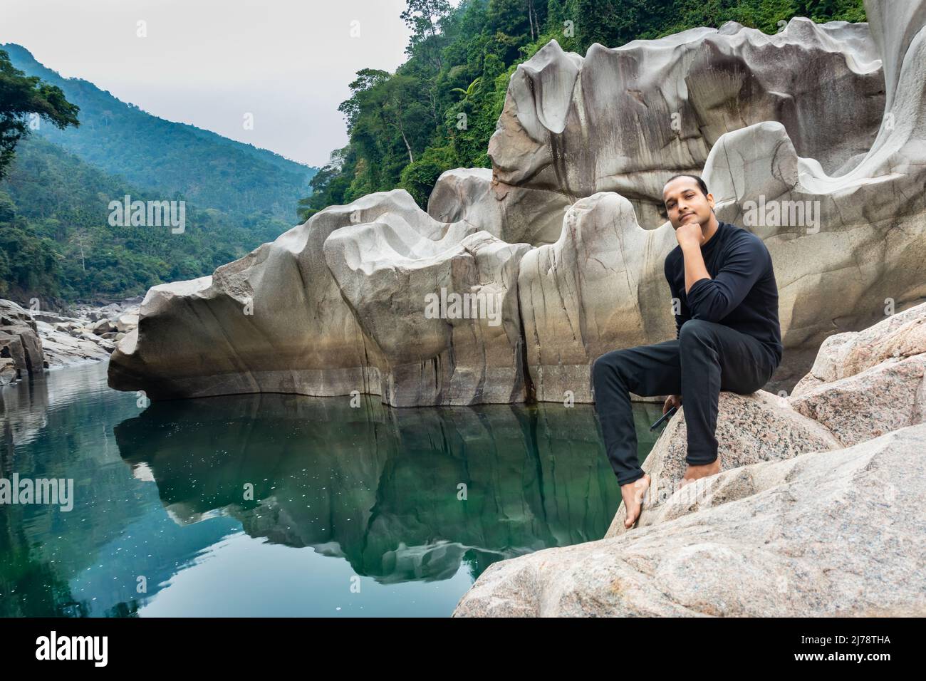 Jeune homme isolé assis sur une pierre blanche brillante naturellement formée dans une forme unique au lit sec de rivière image est prise à Sliang wah Umngot amkoi jaintia hi Banque D'Images