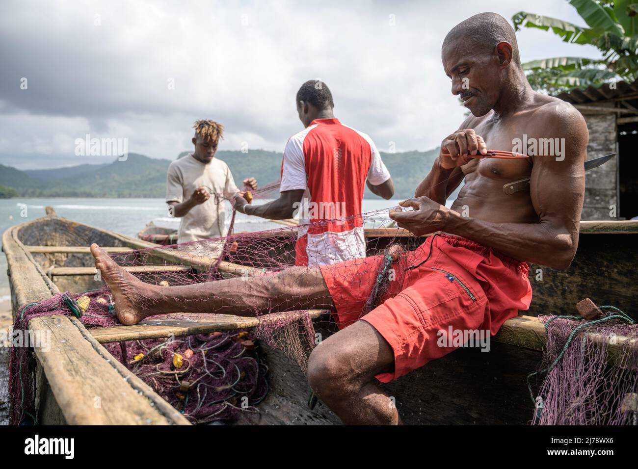 Les pêcheurs réparent les filets de pêche sur le canot avant de partir pêcher. Banque D'Images