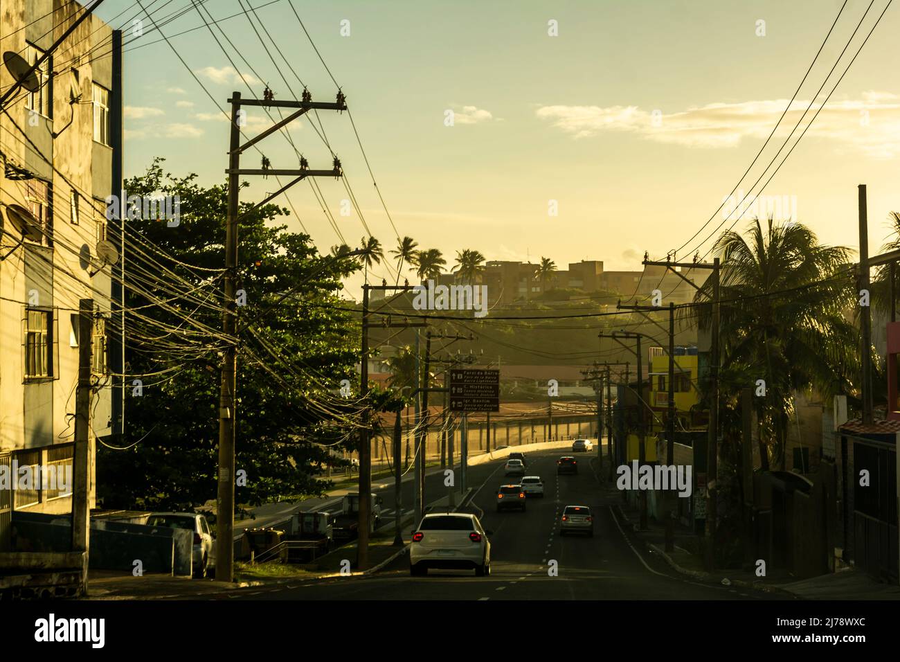 Coucher de soleil déversant les bâtiments et les voitures d'une rue dans le quartier de Rio Vermelho. Voitures passant. Salvado Banque D'Images
