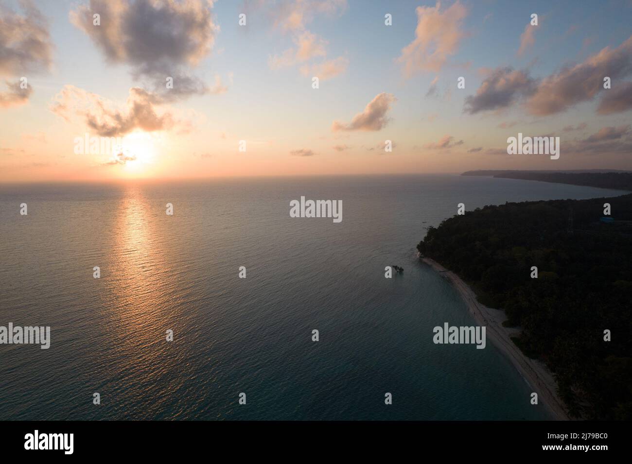 tir de drone aérien allant du lever du soleil orange rouge à l'horizon à l'île couverte de cococotier vert à l'aube crépuscule aux îles swaraj dweep havelock langkawi Banque D'Images