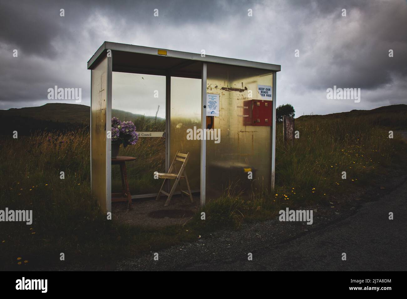 Eclairage naturel stupéfait sur Scottish Highlands bus Shelter avec chaise et fleurs, île de Skye, Écosse Banque D'Images