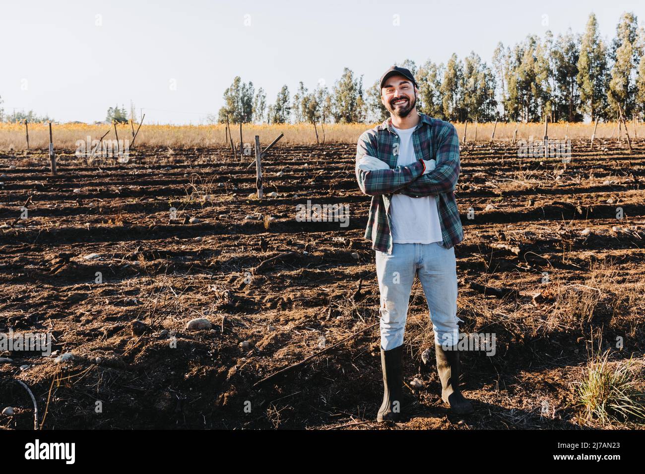 Gros plan d'un agriculteur latin avec des armes croisées au milieu des terres agricoles. Banque D'Images