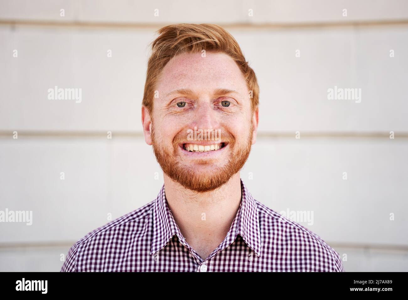 Portrait extérieur d'un homme souriant de cheveux rouges regardant l'appareil photo riant avec le visage positif et le regard amical. Gros plan sur un visage humain heureux - Banque D'Images