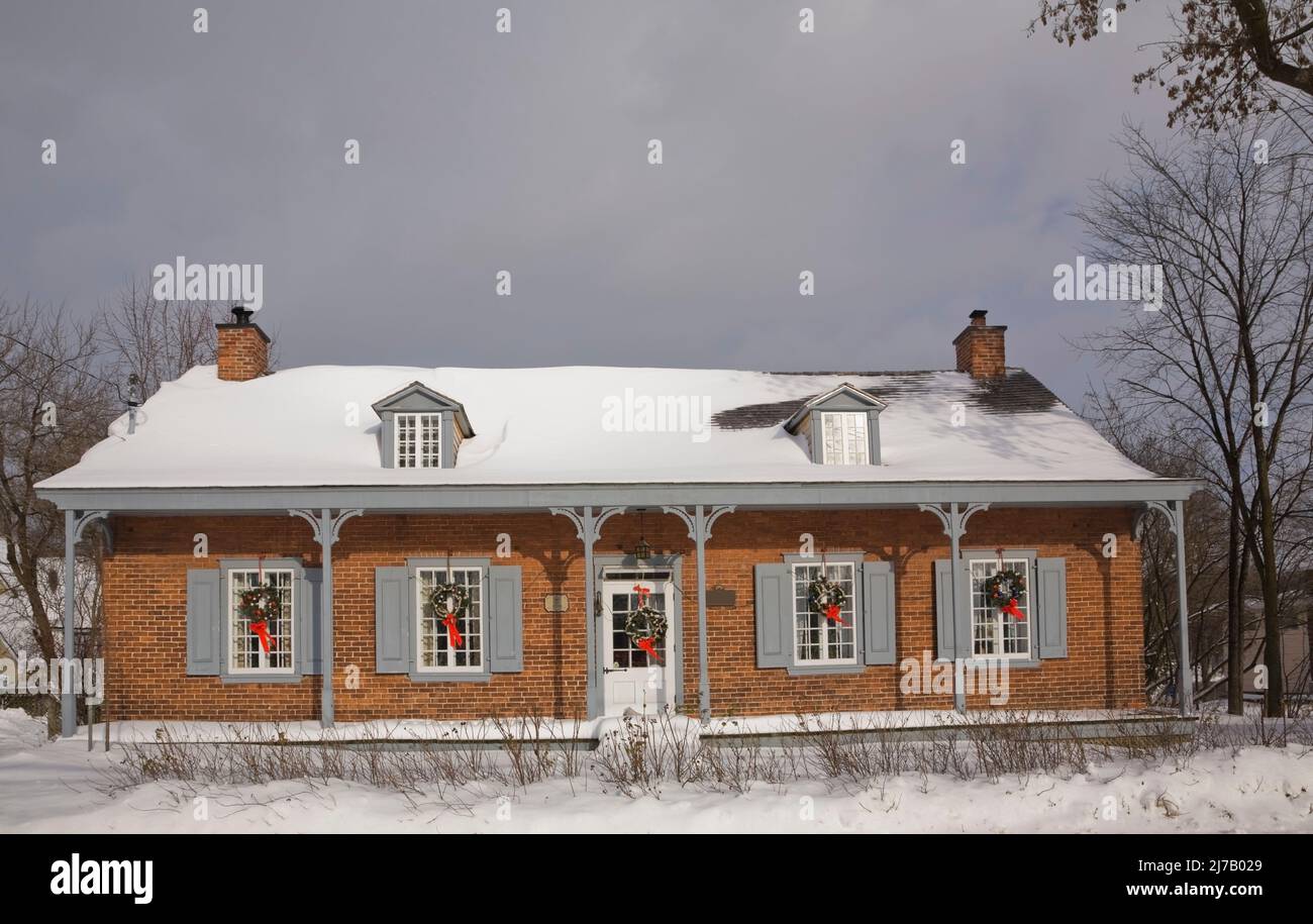Ancienne maison en briques nuancées rouges de style Canadiana 1800s décorée de couronnes de Noël sur la façade en hiver. Banque D'Images