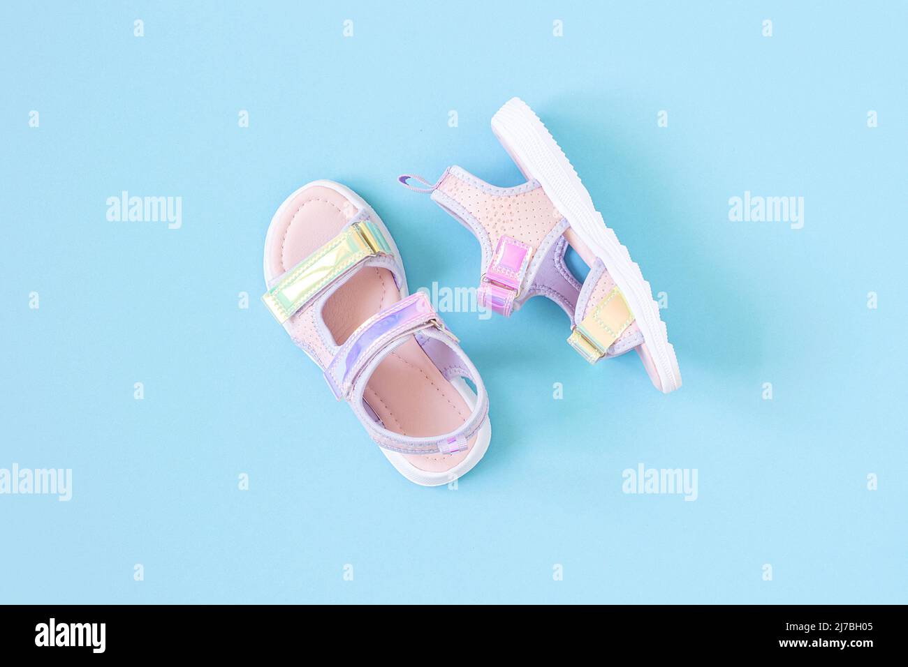 Sandales holographiques élégantes pour enfant sur fond bleu. Chaussures d'été à la mode. Flat Lay, vue de dessus. Banque D'Images