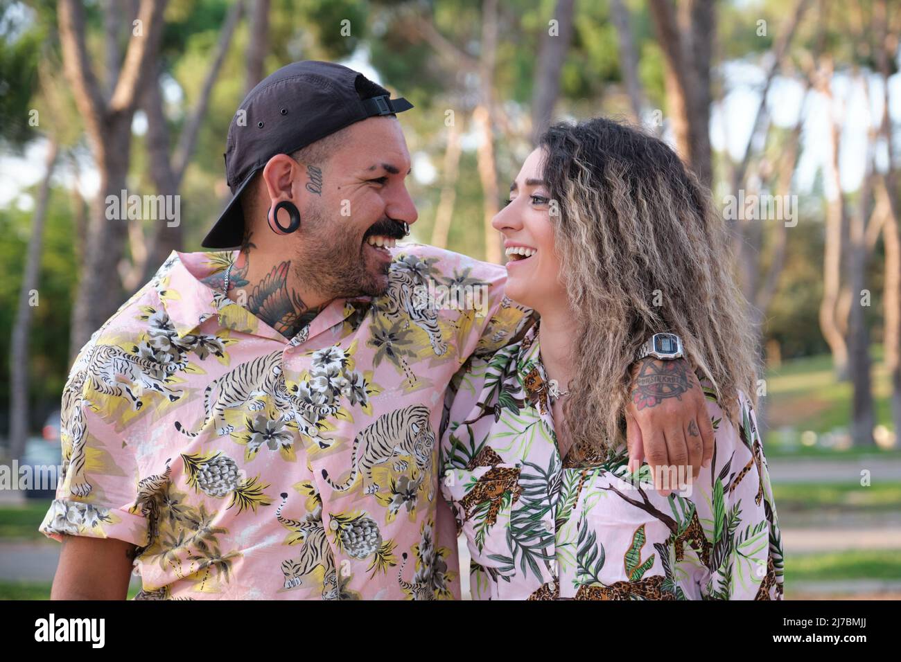 Jeune couple cool tatoué regardant l'un l'autre et rire. Banque D'Images