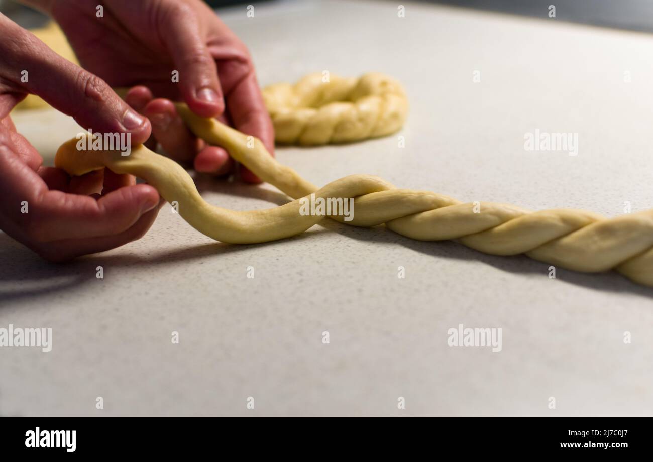 Les mains de femmes braissent la pâte sur une table blanche, gros plan Banque D'Images