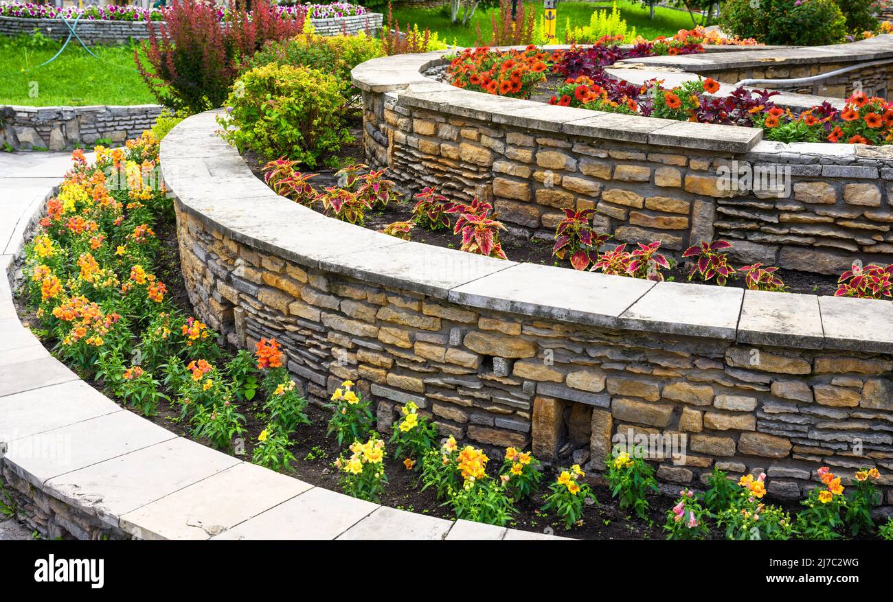 Aménagement paysager avec murs de soutènement et parterres de fleurs dans l'arrière-cour de la maison résidentielle. Aménagement paysager du jardin haut de gamme de la maison en été. Fleurs et plantes o Banque D'Images