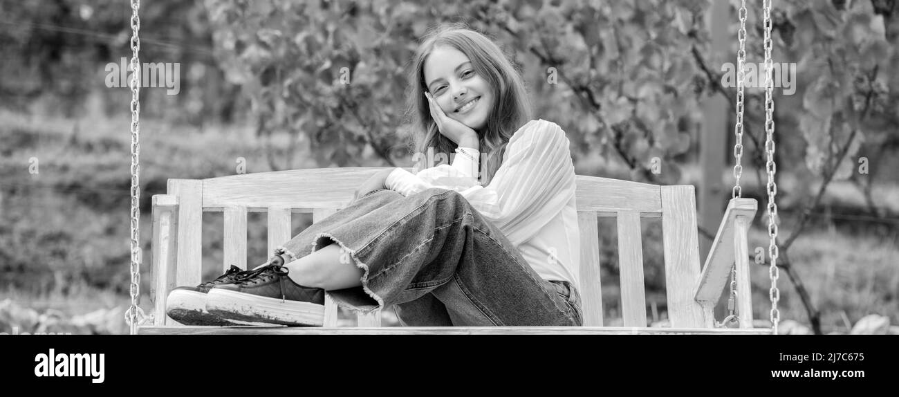 sourire enfant assis sur balançoire dans le parc, bonheur Banque D'Images