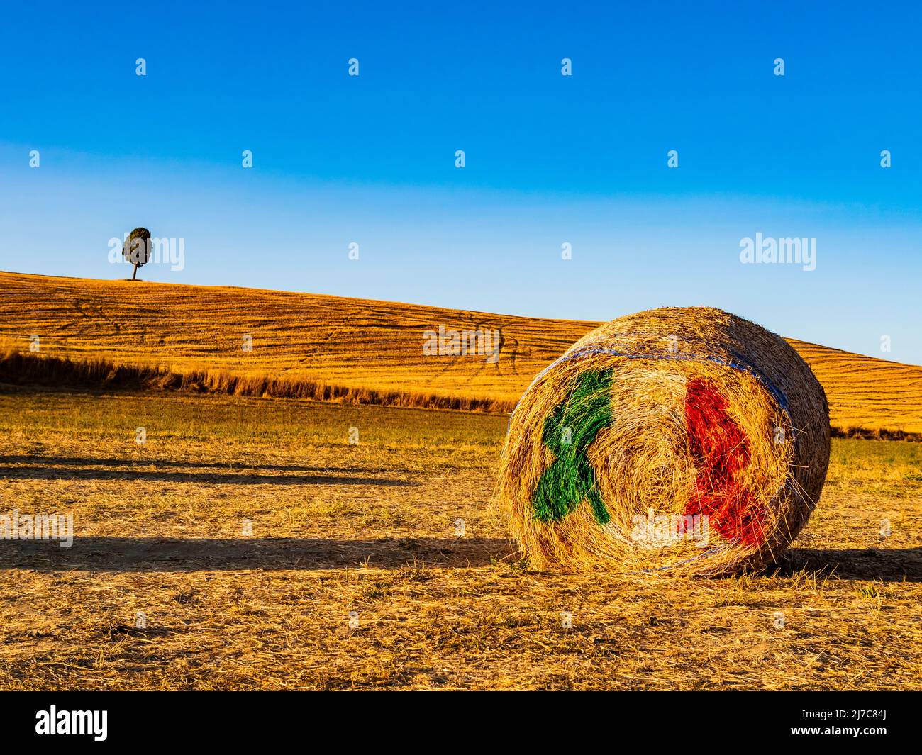 Magnifique paysage toscan avec colline vallonnée et balle de foin avec drapeau italien en premier plan Banque D'Images