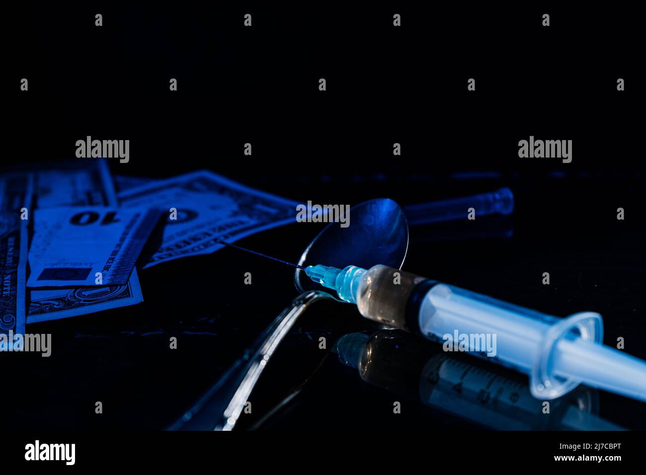 Argent et drogues. Billets de banque et simulation de drogues telles que l'héroïne ou la cocaïne sur une surface noire faiblement éclairée. Vue en hauteur. Concept de substances illégales, Banque D'Images