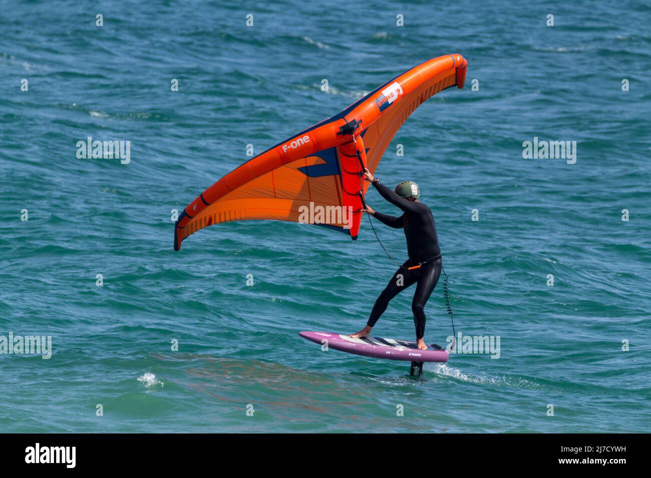 Planche à voile surf à l'aide d'une planche à voile avec des lames hydroglissées sous-marines qui s'élèvent à la surface en mouvement, et une voile gonflable à main Banque D'Images