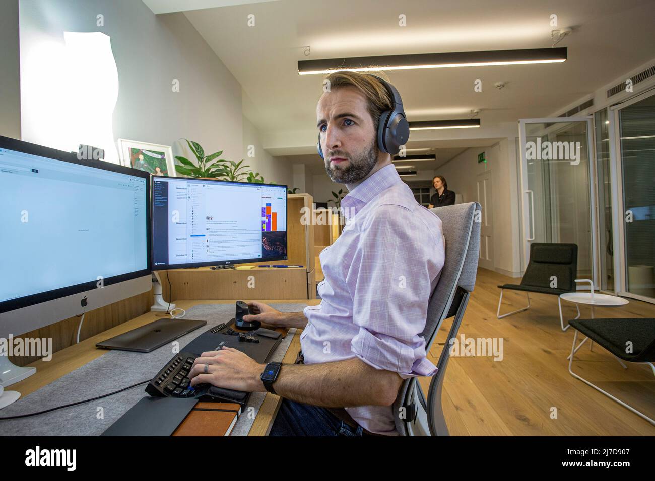 jeune homme décontracté avec micro-casque utilisant un ordinateur dans un bureau Banque D'Images