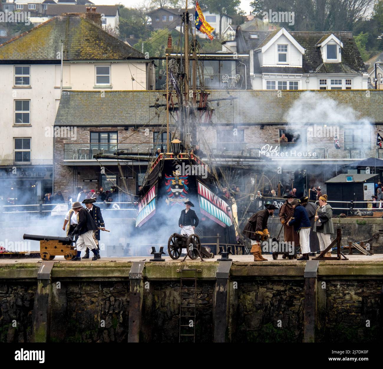 BRIXHAM, DEVON, ANGLETERRE - MAI 1 2022 : les canons sont tirés par des participants en costume de fantaisie, devant le Golden Hind réplique du navire. Banque D'Images