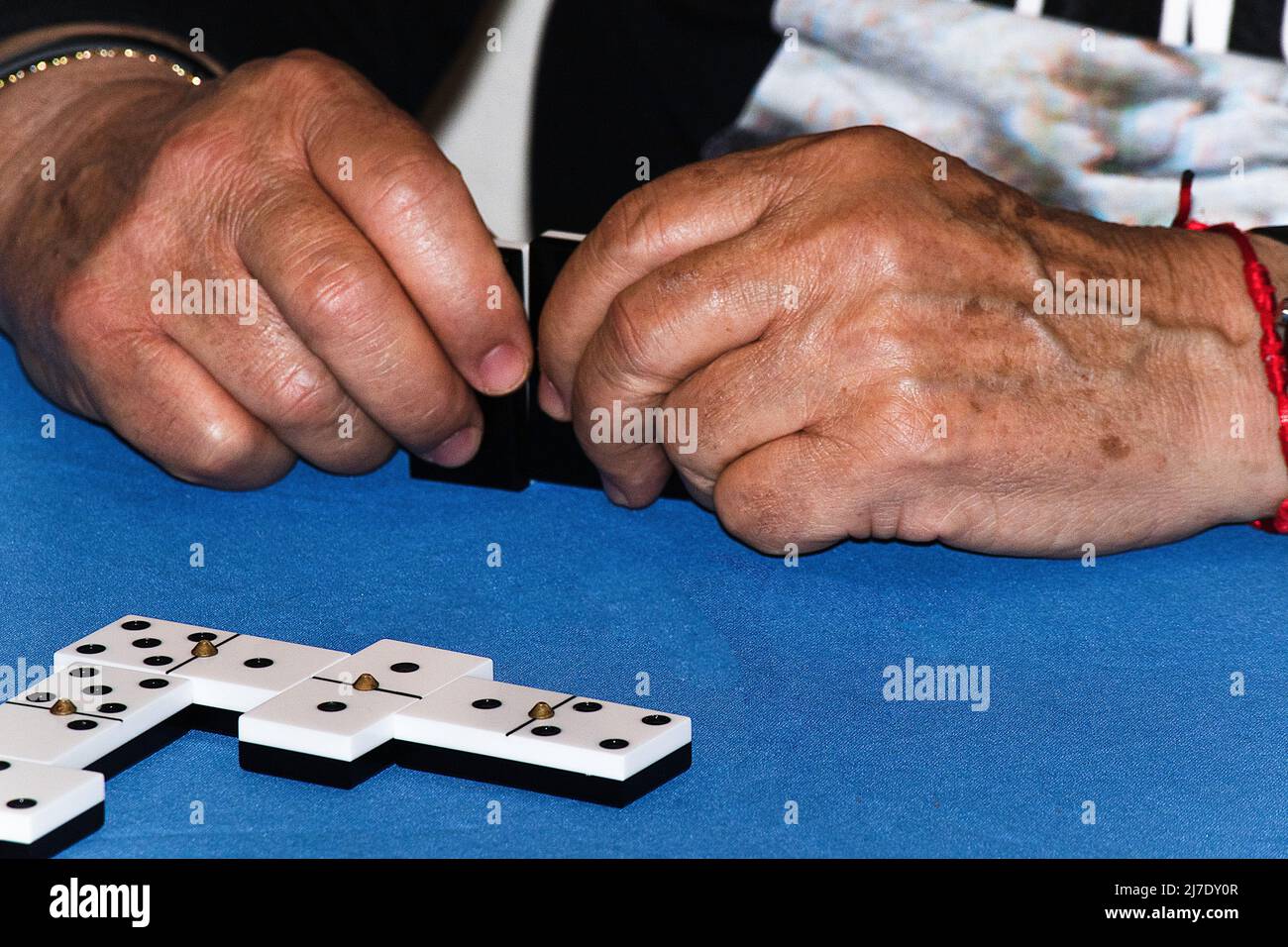 les mains du vieil homme jouent des dominos à la maison Banque D'Images