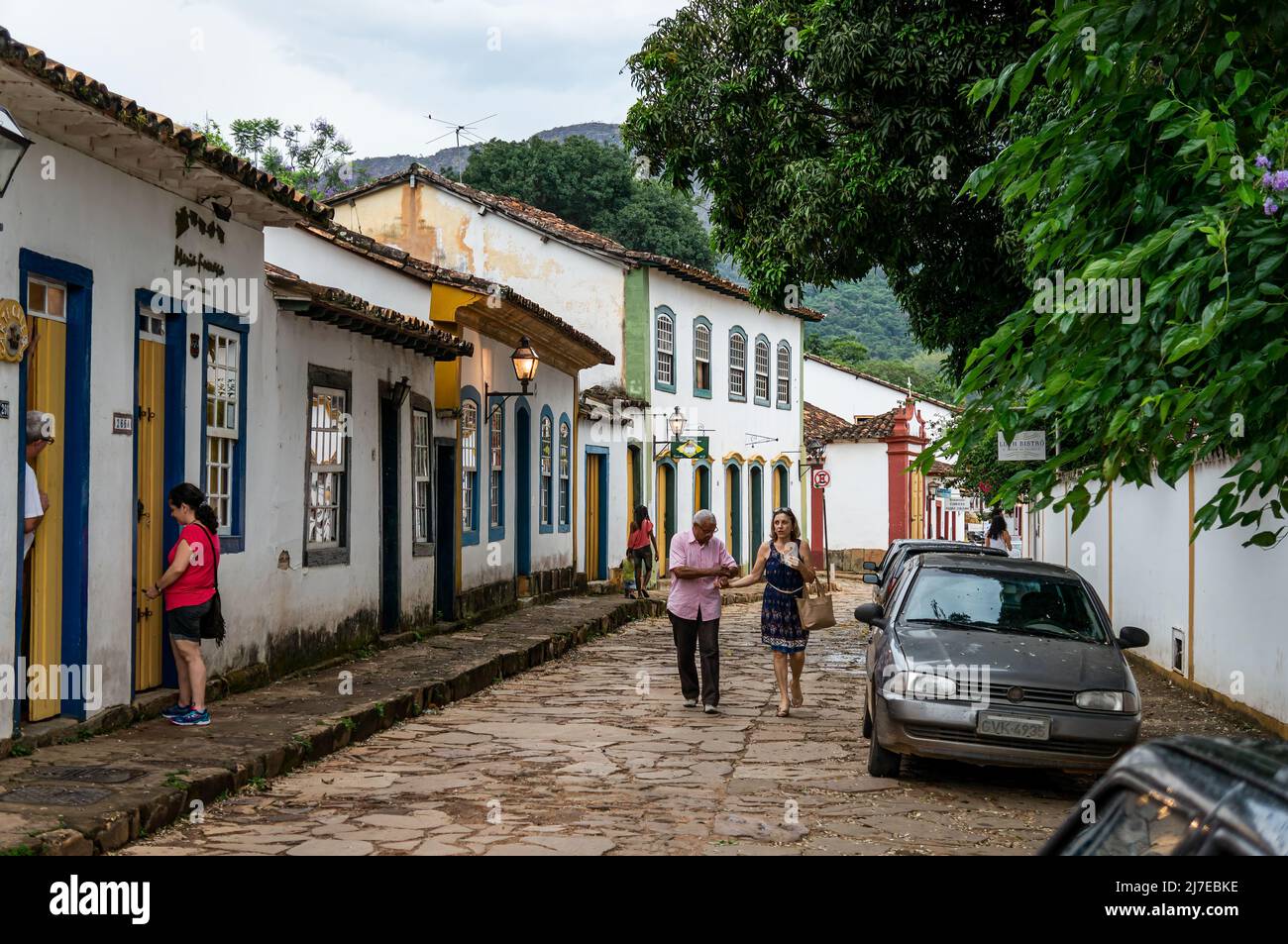 Vue sur la rue de Direita avec une rangée de maisons coloniales côte à côte et des piétons qui marchent dans le centre historique de Tiradentes sous un ciel nuageux. Banque D'Images