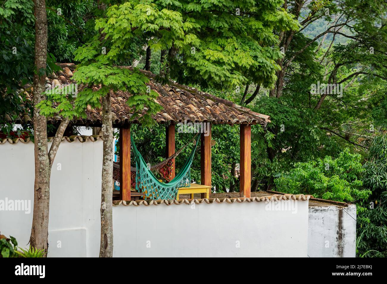 Un espace extérieur avec des hamacs de jardin colorés sous un toit de tuiles zone extérieure couverte d'une maison voisine comme vu de la rue Direita. Banque D'Images