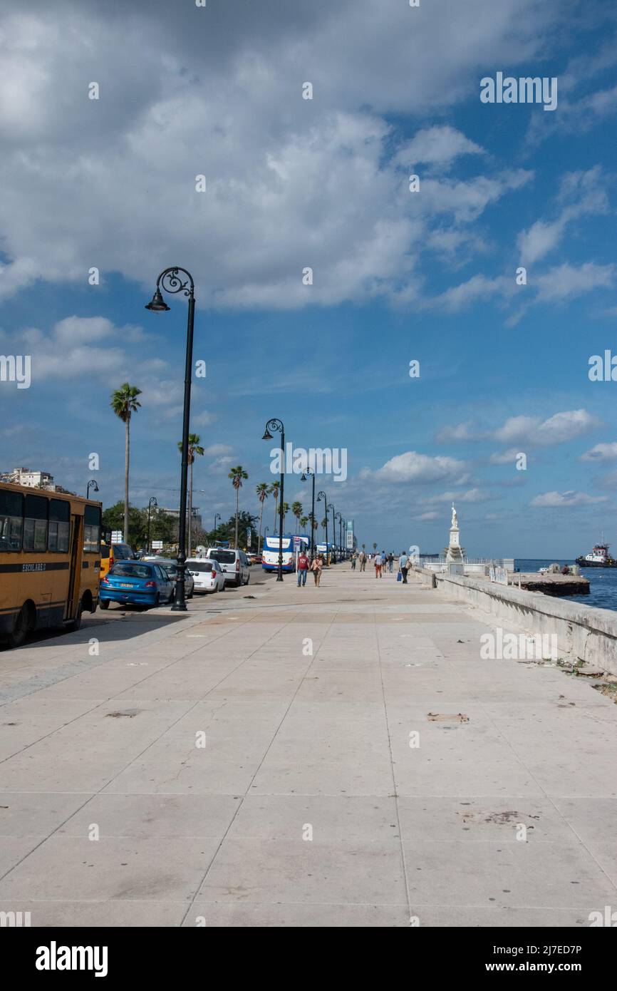 Touristes marchant sur le Malecon à la Havane, Cuba. Le Malecón est une vaste esplanade, route et digue qui s'étend sur 8 km le long de la côte à HAV Banque D'Images