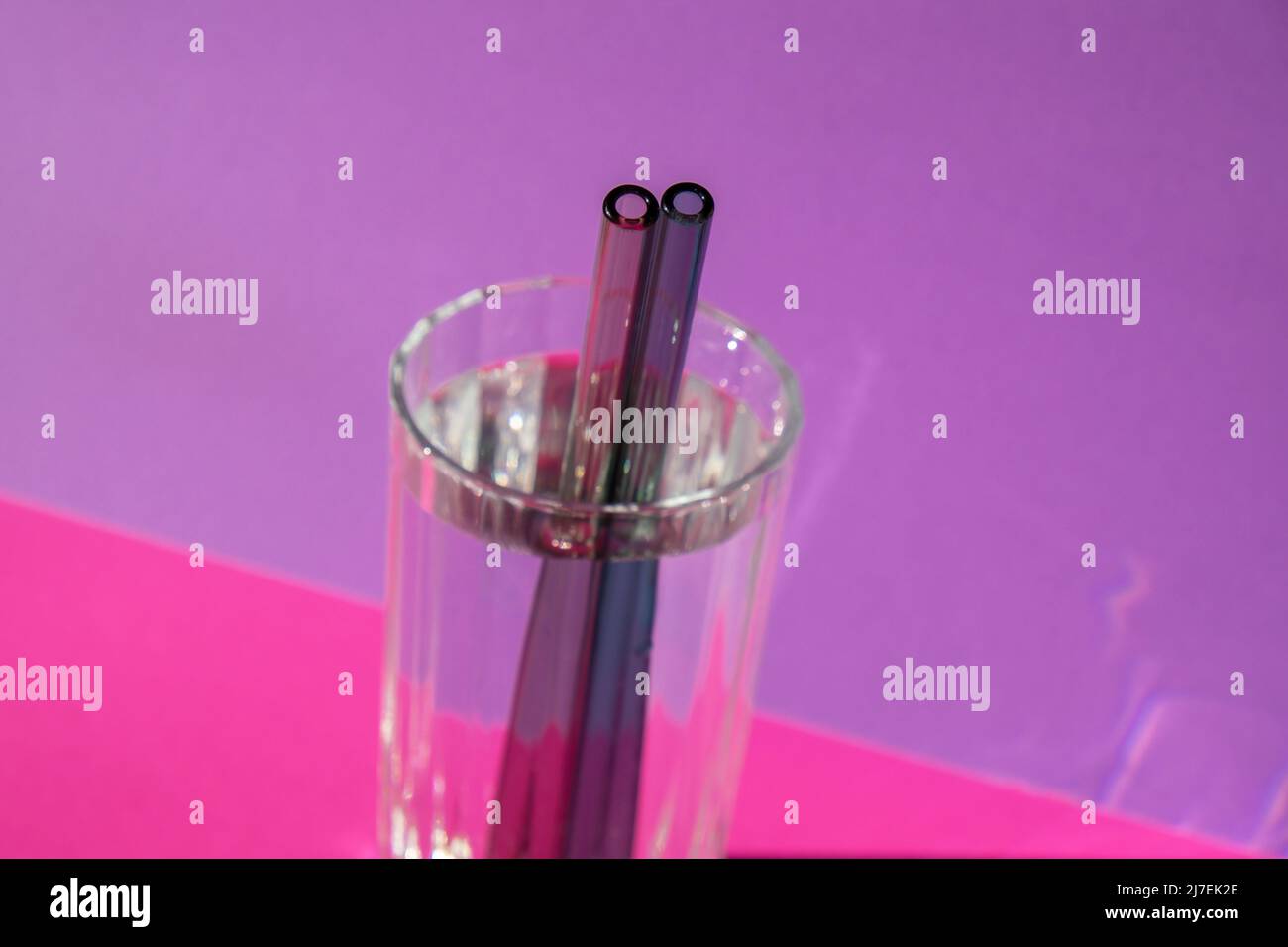Pailles en verre réutilisables en verre avec eau sur fond violet violet ensemble de pailles écologiques avec brosse de nettoyage. Concept sans déchets, sans plastique. Style de vie durable. Vie sans déchets peu de déchets Banque D'Images