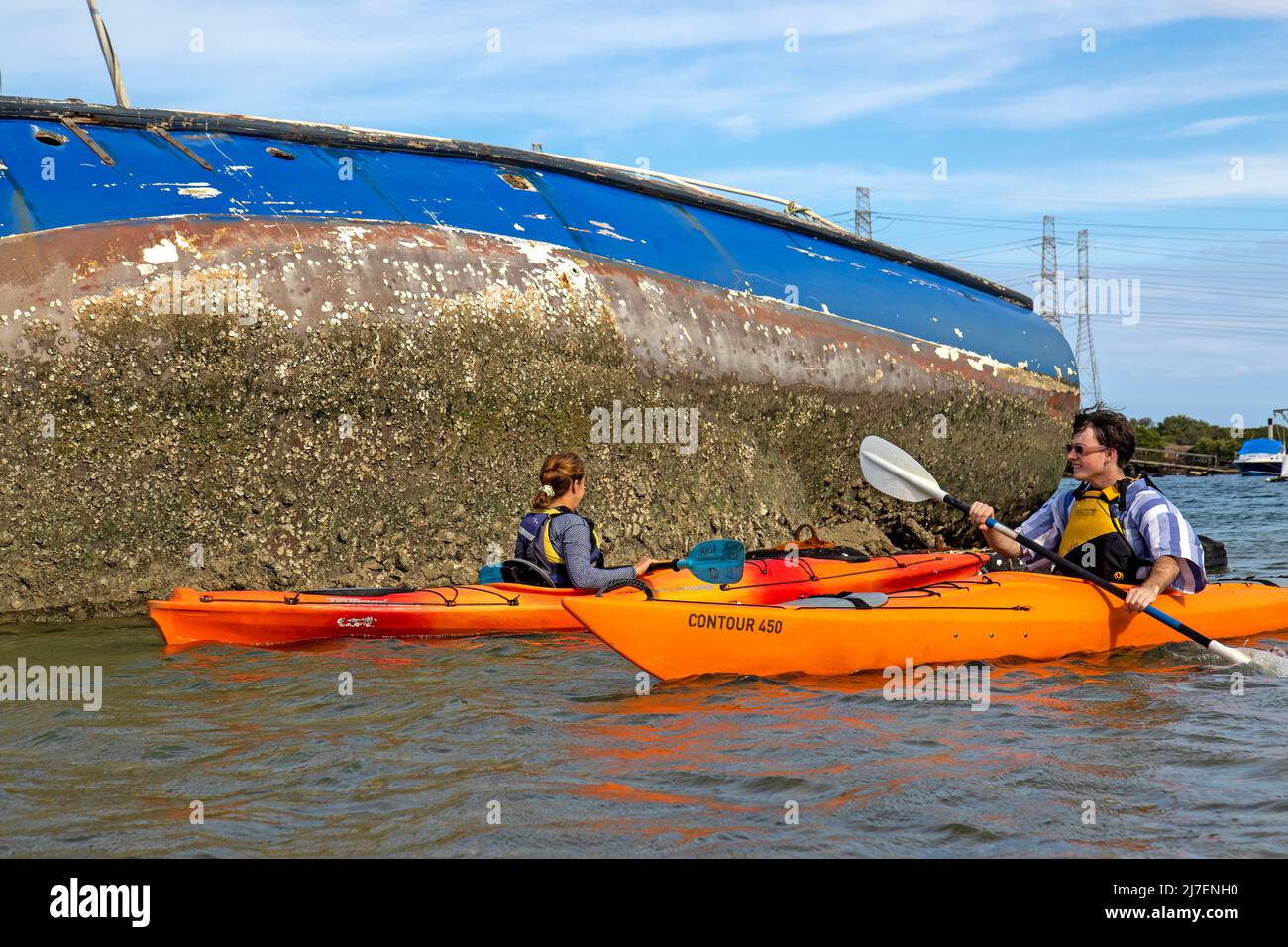 Faire du kayak en passant devant un yacht épaté dans la rivière Port Banque D'Images