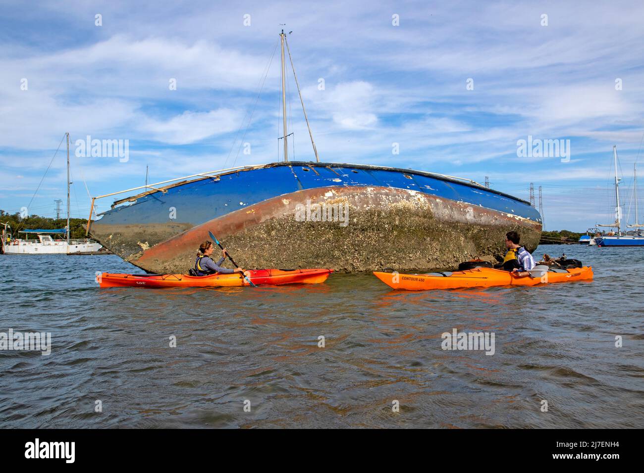 Faire du kayak en passant devant un yacht épaté dans la rivière Port Banque D'Images